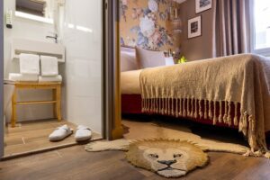 welcome hotel rive gauche paris : chambre avec chaussons dans la salle de bain, tapis lion, lit et couvre lit