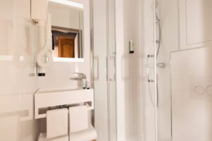 chambre single supérieure paris : salle d'eau avec douche, lavabo et serviettes blanches