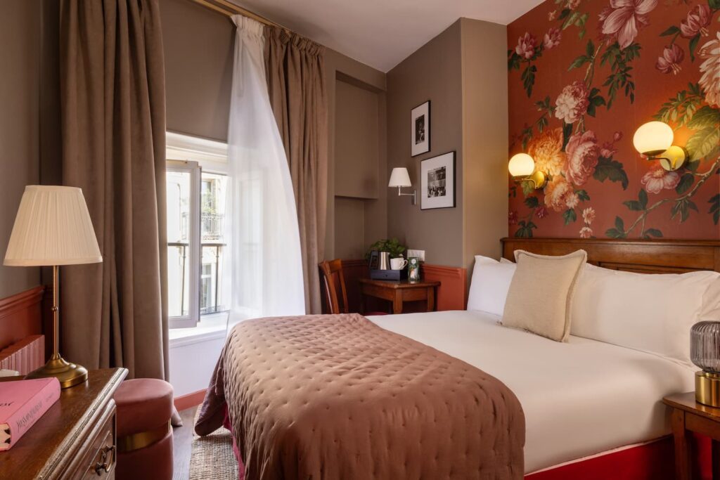 Chambre single supérieure WELCOME HOTEL paris centre - vue de la chambre avec fenêtre ouverte, lit blanc et édredon rose, cadres photo en noir et blanc