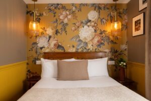 welcome hotel rive gauche paris : lit, coussin, tissu jaune fleuri et photos en noir et blanc de Paris