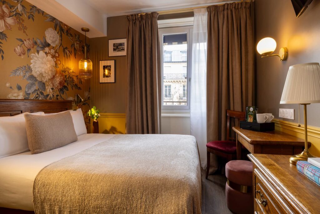 hotel chambre double paris : lit double, large fenêtre sur rue, tissu jaune fleuri