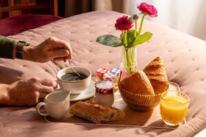 petit déjeuner en chambre hotel rive gauche : plateau de petit-déjeuner sucré posé sur le lit avec fleurs