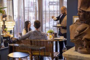 Service du petit-déjeuner au welcome hôtel paris - le serveur verse du thé devant le jeune couple attablé - hiver à paris